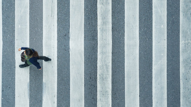 the top view of person walk across the pedestrian crosswalk in white and grey pattern