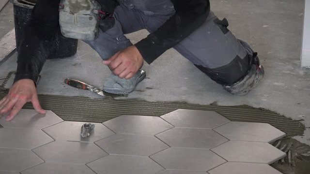 Professional worker laying hexagon stone mass tiles on floor