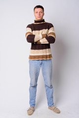 Full body shot of young man wearing turtleneck sweater with arms crossed