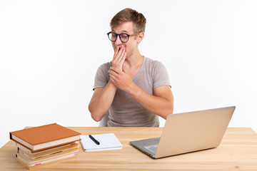 People and education concept - Funny student man sitting at the wooden table with laptop and books