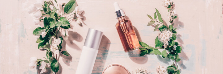 Natural organic cosmetics: serum, cream, mask on wooden background with flowers. Spa concept