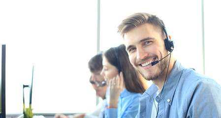Portrait of call center worker accompanied by his team. Smiling customer support operator at work.