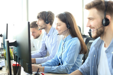 Fototapeta premium Portrait of call center worker accompanied by her team. Smiling customer support operator at work.