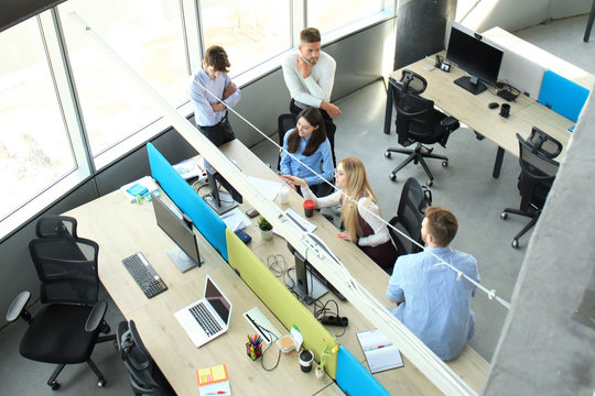 Top view of young modern colleagues in smart casual wear working together while spending time in the office.