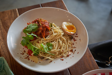 Spaghetti with tomato sauce and egg on wooden table