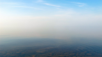 Quiet background, landscape with a smooth surface of a lake with calm water to the horizon