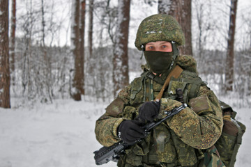 Fototapeta premium A girl stands with a gun. Winter. Army. A man stands with a gun. Russian soldier with AK-74.