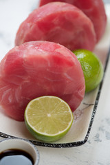 Raw yellowfin tuna medallions and limes, selective focus, closeup, vertical shot