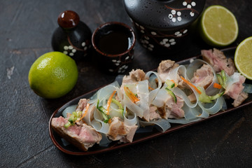 Noodles with slices of fried yellowfin tuna fillet, elevated view on a dark brown stone surface