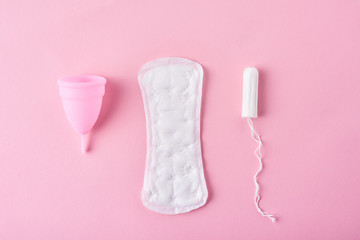 Sanitary pad, menstrual cup and tampon on a pink background