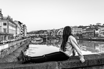 figure of a young woman in contemplation on the bridge of the Arno river in Florence, black and white portrait of adolescence