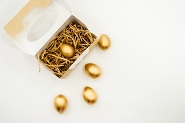 Golden Easter Eggs in a box with golden stars on white background . Easter Holiday concept abstract background copyspace top view
