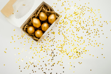 Golden Easter Eggs in a box with golden stars on white background . Easter Holiday concept abstract background copyspace top view