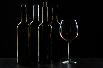 Bottles of wine and different glasses of wine on a dark background