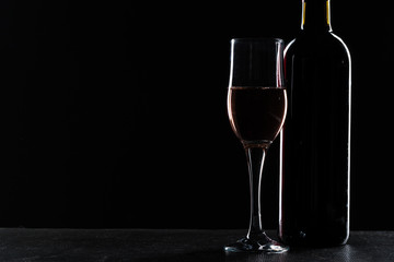  wine bottle and wine glass in a black background