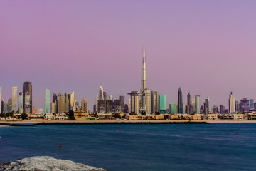 Fototapeta na wymiar Futuristic Skyscraper buildings view from beach island with blue waterfront and twilight sky background