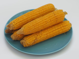 Five ears of boiled corn on a plate. Tasty and healthy organic food from the farmer. Vegetarian table. Fresh product from yellow grains. 