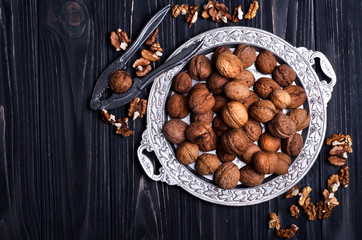 Walnuts in a silver dish on a dark wooden background