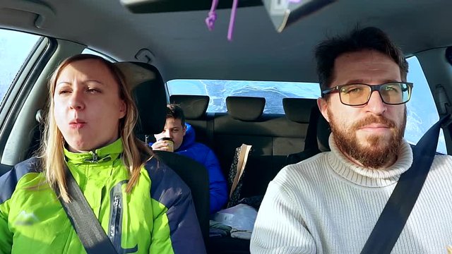 Family dad, mom and son eat in the car sandwich. They drive in a car on a winter road