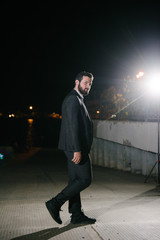 A man in a gray suit posing on the street at night. Advertising of men's clothing.