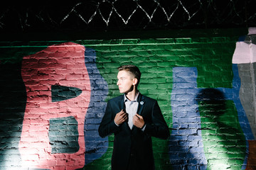 A man in a blue suit posing on the street at night. Advertising of men's clothing.