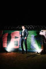 A man in a blue suit posing on the street at night. Advertising of men's clothing.