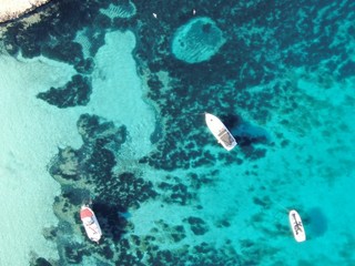 Vistas aereas de una cala  de Mallorca sobre unas aguas color turquesa con unos barcos anclados 