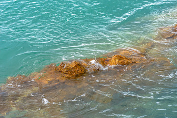 Obraz premium Sea waves breaking on a rocks. Deep blue sea waves hit cliff, hit rocks cliff. Mighty sea waves breaking on a cliff, splashing over rocks. Strong ocean waves hitting rocks.
