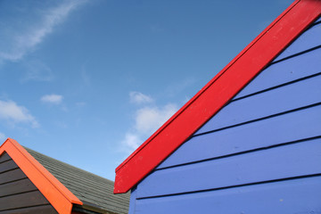 Fototapeta na wymiar Colorful English beach huts against a blue sky