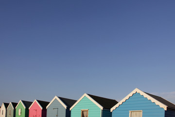 Colorful English beach huts against a blue sky