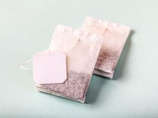 Two tea bags with white label isolated on light background