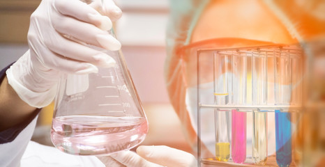 Scientist is looking at erlenmeyer flask to observe the chemical reaction in chemical laboratory.