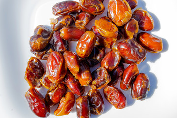 sweet dried dates lie on a white plate, bright sunlight