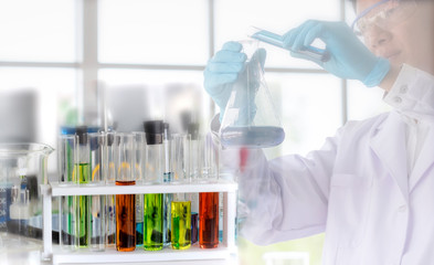 Blurred picture of scientist is pouring the chemical reagent from tube to erlenmeyer flask to...