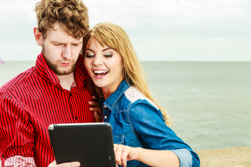 Young couple with tablet by seaside outdoor