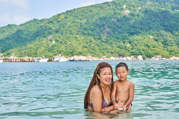 Fototapeta premium Mom and son Asians bathe in the sea