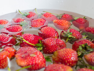 Strawberries are floating in the water for cleaning