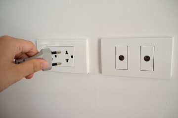 Hand putting plug in electronic power socket