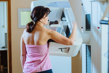 Female patient undergoing mammography test in hospital. Back view, selective focus - obrazy, fototapety, plakaty