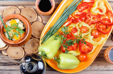 Traditional rustic home vegetable stew with raw vegetables, spices in clay pots with red  wine on old vintage wooden table.