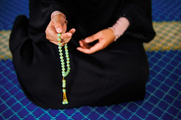 Close up view of woman hands dzikir to Allah while holding a prayer beads