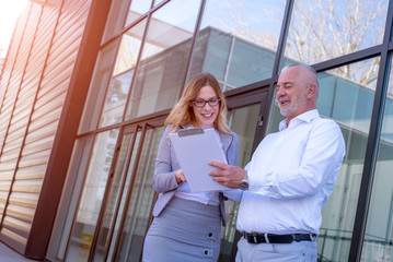 Colleagues and business people checking data in front of an office building