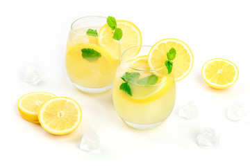A photo of homemade lemonade in glasses, with fresh lemons, mint, and ice cubes, on a white...