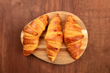 Naklejka na ściany i meble Three croissants, shot from the top on a dark rustic wooden background with copy space