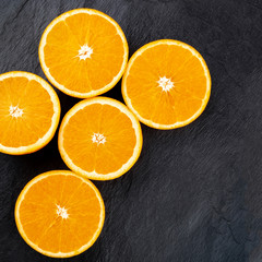A closeup photo of vibrant orange halves, shot from the top on a black background with a place for text