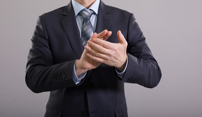 Businessman clapping his hands on a gray background.