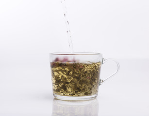 Tea pouring into glass cup isolated on white background