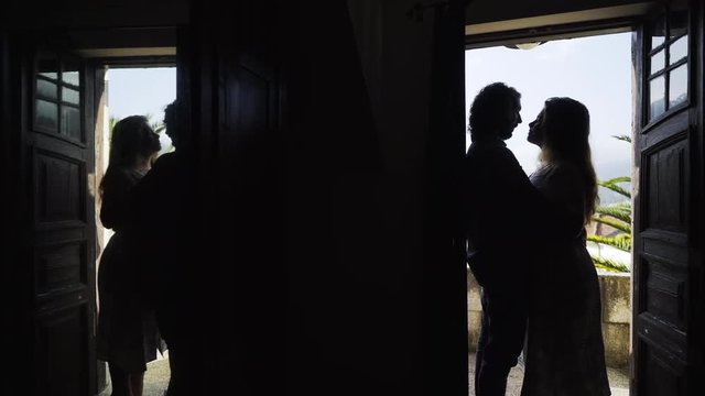 Side view of silhouette couple standing in door frame hugging and kissing near balcony of traditional country house with mirror. Valley of Douro river in winemaking region in Portugal
