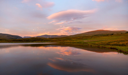 Fototapeta na wymiar Summer landscape in the tundra with a lake in the mountains in sunrise