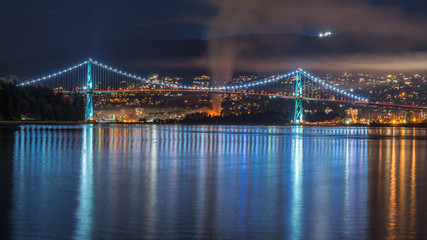 Fototapeta premium Vancouver, British Columbia. Canada Long exposure from below of the Lions Gate Bridge with lights trail, glitters and clouds.